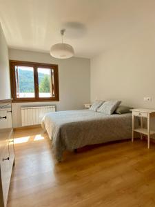 Dormitorio blanco con cama y mesa en Apartamento Balcón del Ésera en Villanova