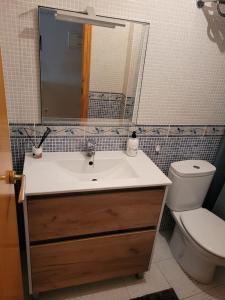 een badkamer met een wastafel, een toilet en een spiegel bij Apartamento en el Grau de Moncofa entre 2 y 3 linea de playa in Moncófar