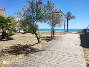 een houten pad naar het strand met palmbomen bij Apartamento en el Grau de Moncofa entre 2 y 3 linea de playa in Moncófar