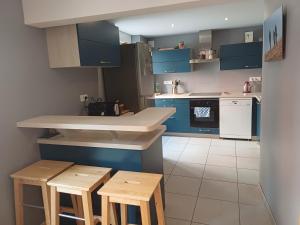 a kitchen with blue cabinets and wooden stools at Le grenier à sel, Chaleureux 2 Chambres-Centre-Gare in Reims
