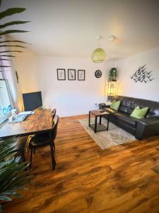a living room with a black leather couch and a table at VALE VIEW APARTMENT, Prestatyn, North Wales - a smart and stylish, dog-friendly holiday let just a 5 min walk to beach & town! in Prestatyn