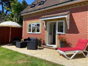 a brick house with a chair and an umbrella at Honey Cottage in Totland