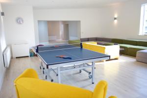 a ping pong table in a room with yellow chairs at Rock House Sligo in Riverstown