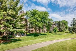 an apartment complex with trees and a driveway at Modern Golfview Condo near the Grand Traverse Bay in Williamsburg