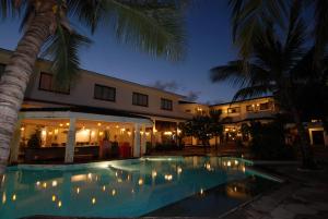 a swimming pool in front of a building at night at Baobab Holiday Resort in Bamburi