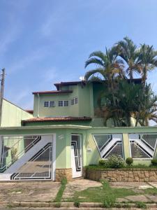 uma casa verde com uma palmeira em frente em Casa em Aparecida em Aparecida