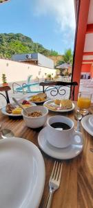 einen Tisch mit Tellern und einer Tasse Kaffee in der Unterkunft A S Suites in Angra dos Reis