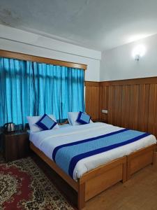 a bedroom with a large bed with blue curtains at Enchanting Tawang in Tawang