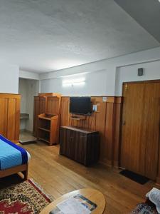 a room with a bed and a tv and wooden cabinets at Enchanting Tawang in Tawang
