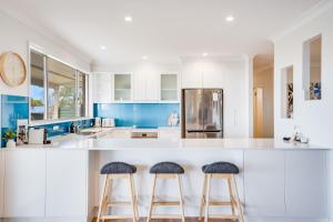 a kitchen with white counters and two bar stools at Becker Bliss - Ocean views, 5 bedrooms, sleeps 12 in Forster