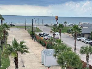 a parking lot with palm trees and the ocean at Casa Del Mar Sun Diamond One Bedroom Retreat - Galveston in Galveston
