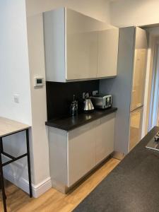 een keuken met witte kasten en een zwart aanrecht bij 2 bed Home from Home Apartment 41 in Londen