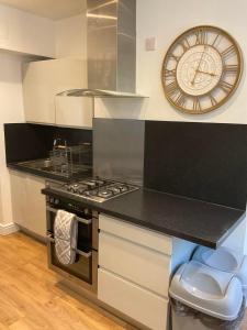 een keuken met een klok aan de muur en een fornuis bij 2 bed Home from Home Apartment 41 in Londen