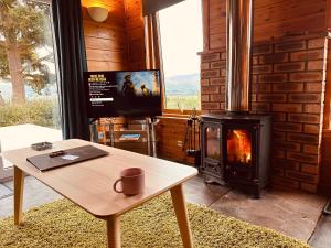 ein Wohnzimmer mit einem Holzofen und einem Tisch in der Unterkunft Kinnaird Woodland Lodges in Pitlochry