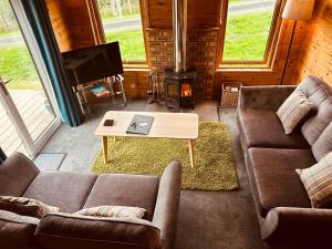 a living room with two couches and a fireplace at Kinnaird Woodland Lodges in Pitlochry
