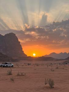 a car parked in the desert with the sun setting at Wadi Rum Desert Bedouins in Wadi Rum