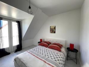 Dormitorio blanco con cama con almohadas rojas en Maison entière 5 mn Roissy CDG/15 mn Parc Astérix en Le Mesnil-Amelot