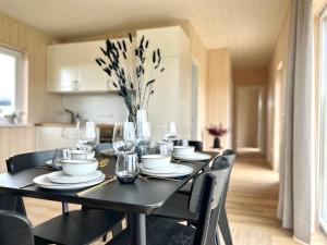 una mesa de comedor negra con sillas y un jarrón de flores en REY Stays - House, en Höfn