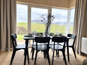 a black dining room table with chairs and a large window at REY Stays - House in Höfn +29 photos