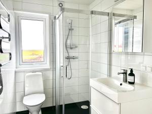 a white bathroom with a shower and a sink at REY Stays - House in Höfn