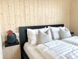 uma cama com almofadas brancas e um vaso sobre uma mesa em REY Stays - House em Höfn