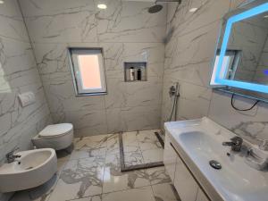 a white bathroom with a sink and a toilet at Apartment Sweet 21 in Tirana