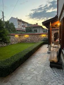 un jardín con una pared de piedra y un banco en Guest House EGO, en Bratsigovo