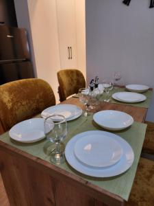 a table with white plates and wine glasses on it at Apartment Sweet 21 in Tirana