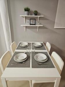 a white dining room table with white plates and chairs at Apartments Zarate in Granada