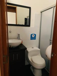 y baño con aseo, lavabo y espejo. en Hostal Zaguán Caldense, en Manizales