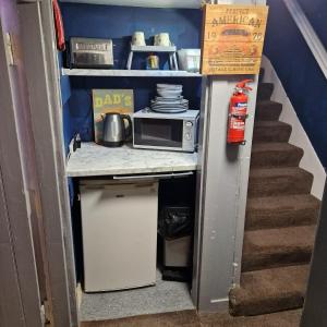una pequeña cocina con microondas y una escalera en Hide away (Central Inverurie) en Inverurie
