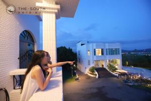 a woman standing on a balcony looking at a building at The South-Dawn in Hengchun