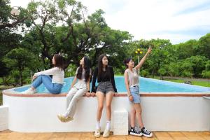 four girls sitting on a wall in front of a pool at The South-Dawn in Hengchun