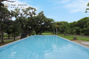 a large swimming pool in a park with trees at The South-Dawn in Hengchun