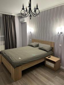 a bedroom with a bed and a chandelier at Апартаменти Люкс 4 in Khmelnytskyi