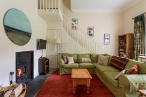 a living room with a green couch and a fireplace at Old Leckie Farmstay in Stirling
