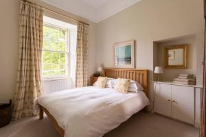 a bedroom with a large white bed with a window at Old Leckie Farmstay in Stirling