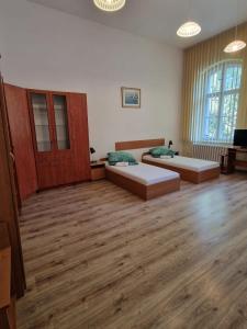 two beds in a large room with wooden floors at Galeona - Hotel turystyczny in Elblag