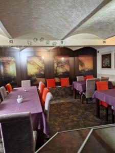 a restaurant with purple tables and chairs and paintings on the walls at Galeona - Hotel turystyczny in Elblag