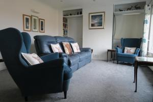 uma sala de estar com cadeiras azuis e sofás em Barr Hill Woods B&B em Kirkcudbright