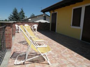 une rangée de chaises jaunes assises sur une terrasse en briques dans l'établissement B&B Da Levi Piana Del Sole, à Rivalta Bormida