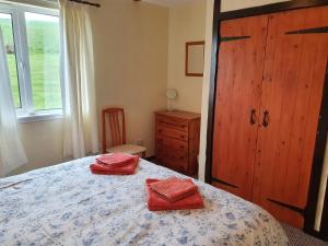 a bedroom with a bed with two red towels on it at Ash Cottage in Stranraer