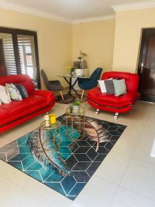 a living room with two red couches and a rug at Kalaji C-Rane Lodge in Phalaborwa