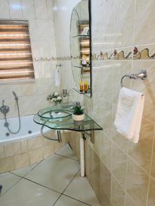 y baño con lavabo de cristal y bañera. en Kalaji C-Rane Lodge, en Phalaborwa