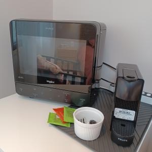 a tv and a cell phone on a shelf at Serenity Indepedent Suite near to Disneyland & Paris in Bussy-Saint-Georges