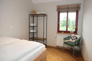 1 dormitorio con 1 cama, 1 silla y 1 ventana en Resilienz und Entspannung pur! Neue LODGE am See - ideal für Gruppen und Familien, en Mustin