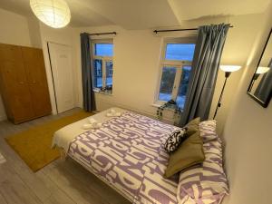 um quarto com uma cama e duas janelas em Luminous Family Flat (4 guests) em Londres