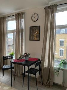 a table and chairs in a room with a clock on the wall at Luminous Family Flat (4 guests) in London