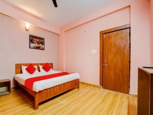 a bedroom with a bed with red pillows and a door at Hotel Crown Square in Bhopal