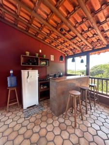 cocina con encimera con taburetes y nevera en Casa Passarinho, en Vale do Capao